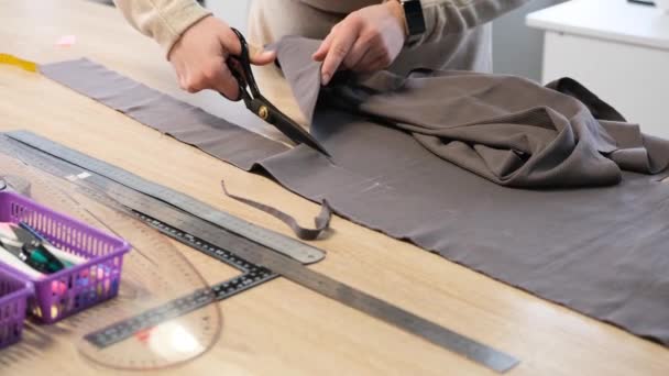 女裁缝师在缝纫车间里用剪子剪裁服装的面料 剪裁的线条与草图的线条一致 — 图库视频影像