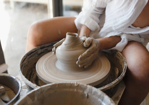 一位年轻的女雕塑家坐在一个陶工的轮子后面 手工制作 制作陶器 — 图库照片