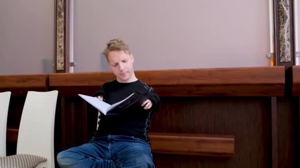 Ένας Άντρας Αναπηρίες Διαβάζει Ένα Βιβλίο Που Κάθεται Στην Αίθουσα — Αρχείο Βίντεο