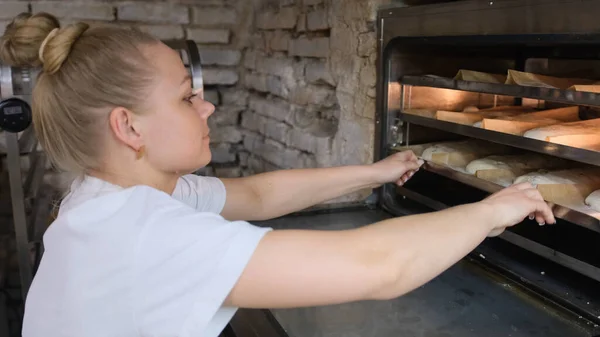 Female Baker Inserts Baking Sheet Oven Bakery — Stock Photo, Image