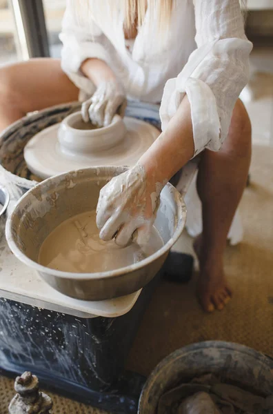 一个女人在一个陶工的车轮后面工作 制作手工餐具 — 图库照片