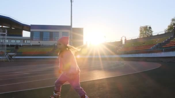 Mała Dziewczynka Uczy Się Jeździć Rolkach Stadionie Latem Zachodzie Słońca — Wideo stockowe