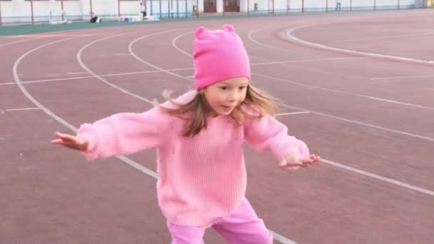 Een Klein Meisje Een Roze Trui Leert Rolschaatsen Het Stadion — Stockvideo