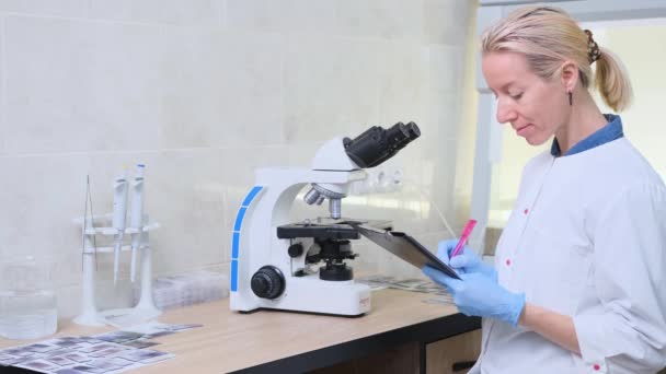 Una Donna Sul Posto Lavoro Guarda Attraverso Microscopio Laboratorio Scrive — Video Stock