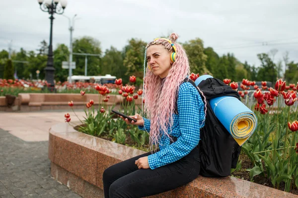 Kulaklıklı Pembe Saçlı Bir Kız Sırtında Sırt Çantasıyla Şehirde Dolaşıyor — Stok fotoğraf