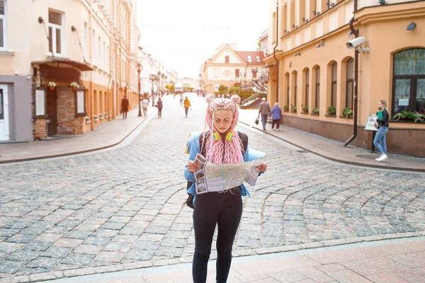 青いシャツを着た魅力的な若い観光客が新しい街を探索しています 長いピンク色の髪の少女は 彼女の手に都市計画の紙の地図を保持しています ヨーロッパ一周旅行 — ストック写真