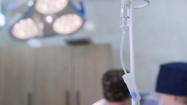Goutte Goutte Médical Pend Sur Trépied Devant Une Équipe Chirurgiens — Video