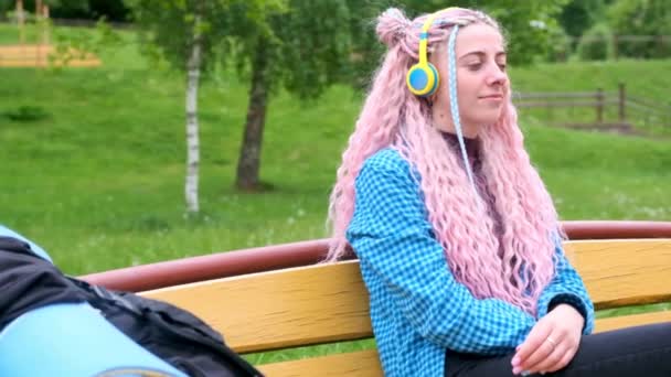 Una Chica Con Pelo Rosa Escucha Música Auriculares Amarillos Sentados — Vídeos de Stock