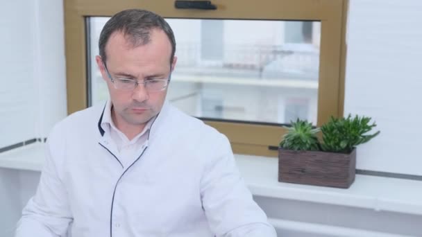 Уставший Доктор Потирает Глаза После Просмотра Фотографии Пациента Сидящего Офисе — стоковое видео