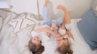 Pijamalı iki kız modern, parlak bir dairede yatakta kavga ediyorlar..