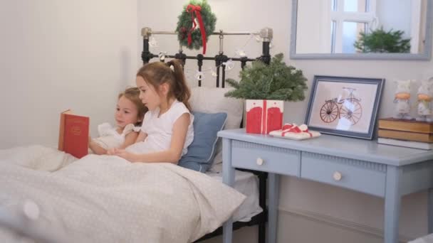 Twee Kleine Meisjes Lezen Een Boek Liggend Hetzelfde Bed — Stockvideo