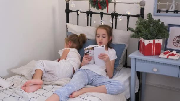 Dziewczyna Czyta Książkę Dla Młodszej Siostry Przed Pójściem Spać Leżąc — Wideo stockowe