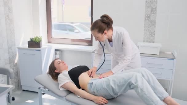 Une Femme Médecin Avec Stéthoscope Examine Abdomen Jeune Patient Couché — Video