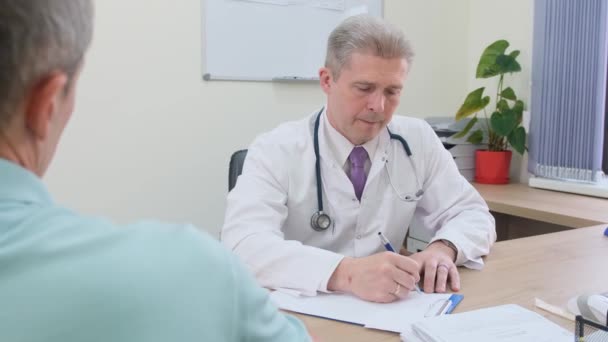 Lékař Který Naslouchá Staršímu Pacientovi Zapisuje Příznaky Starší Muž Schůzku — Stock video