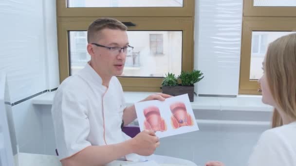 一位男性产科医生在会诊时向医院里的一位女病人展示了一个人直肠的模型 — 图库视频影像