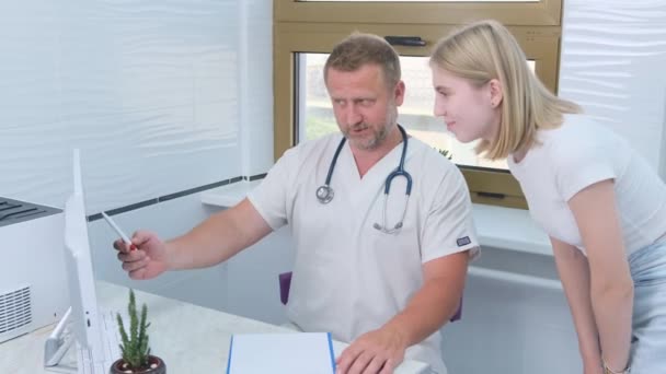 Lekarz Doradza Młodemu Pacjentowi Recepcji Wyjaśnia Pokazuje Wyniki Badań Lekarskich — Wideo stockowe