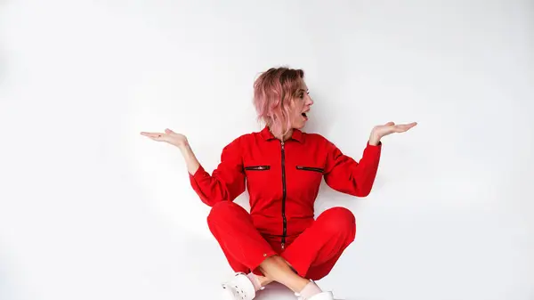 Een Mooie Vrouw Een Rood Jumpsuit Zit Kijkt Verbaasd Naar — Stockfoto