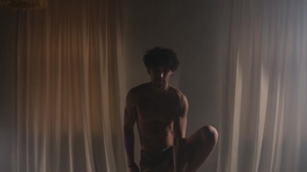 裸のトーソを持つスポーティな若者がスタジオでアクロバティックな動きをする — ストック動画