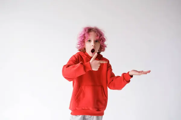 Dziecko Różowymi Włosami Wyrazem Zaskoczenia Twarzy Czerwonym Shircie Wskazuje Palcem — Zdjęcie stockowe