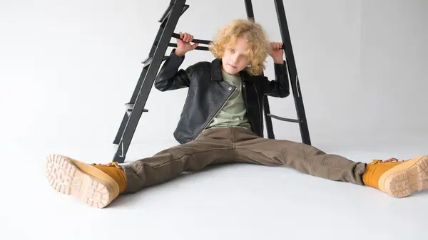 Kıvırcık Saçlı Genç Bir Adam Yerde Oturuyor Bacakları Arka Merdivenlerin - Stok İmaj