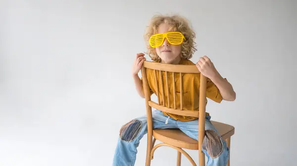 Sarı Gözlük Takan Bir Çocuk Tahta Bir Sandalyede Oturuyor Oyuncak Stok Resim