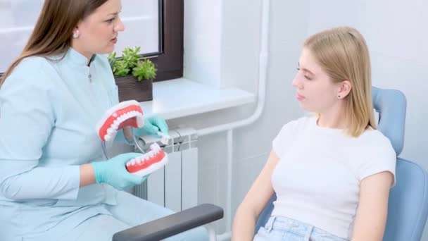 牙科专业人员用一套牙模对年轻妇女进行适当的口腔保健教育 — 图库视频影像