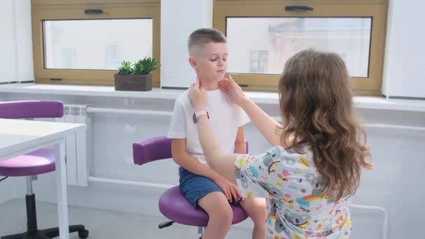 Egy Gyermekorvos Vizsgálja Nyirokcsomókat Egy Kisfiú Nyakán Egy Fényes Klinikán — Stock videók