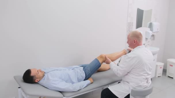 医学考试中 男医生用反射锤敲膝盖 — 图库视频影像