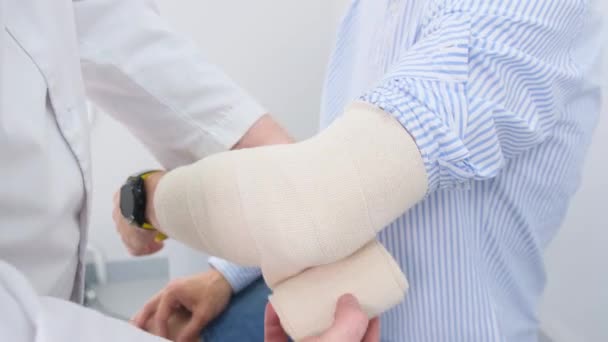Ένας Ιατρός Ασφαλίζει Έναν Επίδεσμο Γύρω Από Ένα Τραυματισμένο Χέρι — Αρχείο Βίντεο