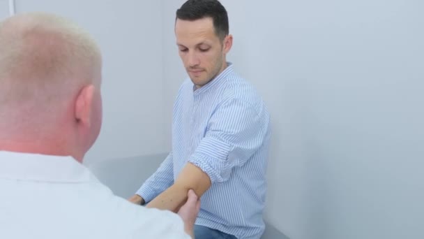 専門の整形外科医が診療所の男性患者の肘を調べる — ストック動画