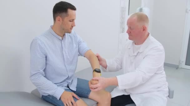 남자는 의사에 검사되고있다 의사는 남자의 팔꿈치 관절을 검사하여 부상이나 비정상적인지 — 비디오