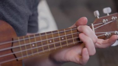 Ukulele tıngırdatan bir adam 4K ile akort yapıyor.
