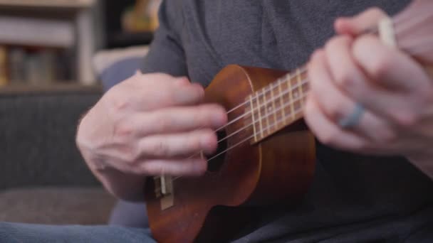 一个男人用4K慢动作弹奏四弦乐和弦 — 图库视频影像