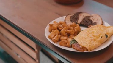 Yumurtalı omlet, patates kızartması ve çavdar ekmeği. Tahta bir masada, 4K 'da.