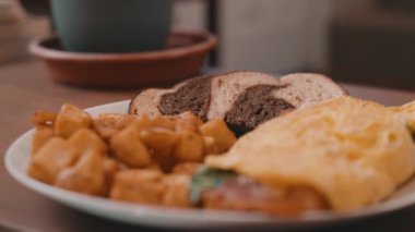 Yumurtalı omlet, patates kızartması ve çavdar ekmeği. Tahta bir masada, 4K 'da.