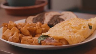 Yumurtalı omlet, patates kızartması ve çavdar ekmeği. Tahta bir masada, 4K 'da.