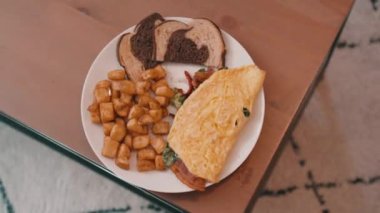 Yumurtalı omlet, patates kızartması ve çavdar ekmeği. Tahta bir masada, 4K 'da.