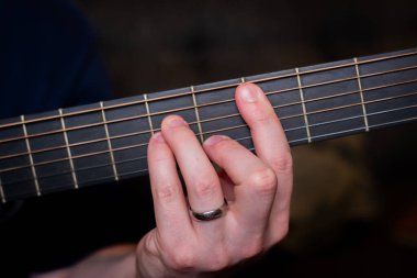 Bir adamın eli akustik gitarda zarifçe bir akor çalar, ruhla yankılanan ahenkli bir melodi dokur.