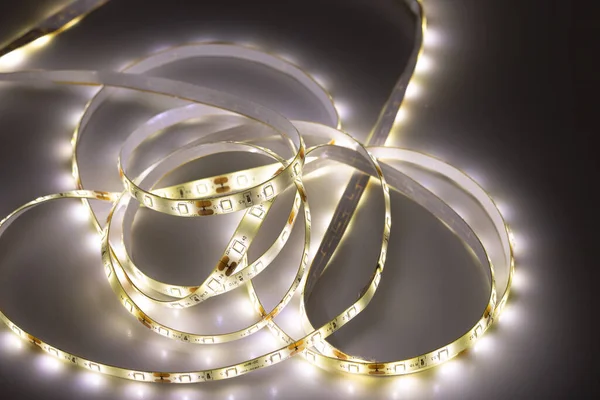 stock image From above of untangled strip of LED light with glowing diodes on shiny surface in darkness