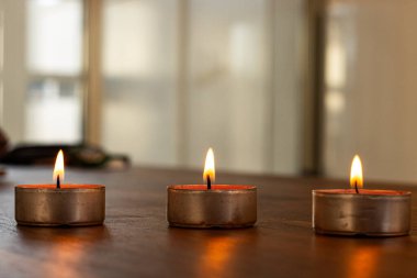 Evde aromaterapi seansı sırasında perdeyle pencereye konmuş mumlar yakılıyor