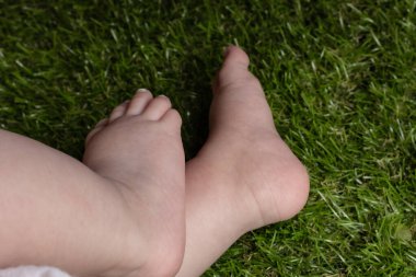 Narin ve narin ayaklı isimsiz bir çocuktan yeşil çimenlerde tek başına otururken ve gün ışığında