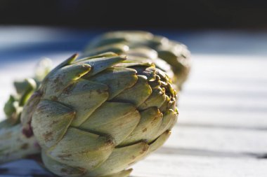 Ahşap bir yüzeye sanatsal olarak yerleştirilmiş taze enginarların yakın plan görüntüsü eşsiz dokularını ve renklerini sergiliyor, aşçılığa ilham ve tazeliği davet ediyor..