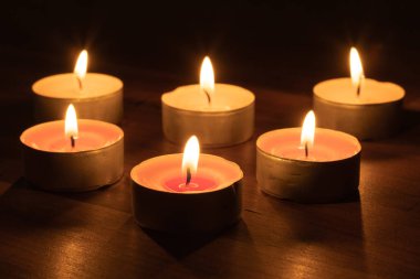 Görüntü, altı yanan çay ışığı mumundan oluşan sakin bir düzenleme içeriyor. Karanlık bir ortamda sıcak ve davetkar bir parıltı yaratıyor. Sakinleştirici bir atmosfer yaratmak için mükemmel..