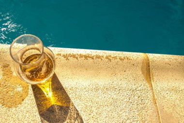 Şeffaf cam sürahisinden havuz kenarına temiz turkuazların yanına serinletici biralar konmuş.