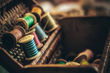 Bu resim, dokuma sepetinde tutulan canlı dikiş ipliklerinden oluşan bir koleksiyon sergiliyor. Tekstil tasarımının ustalığını ve sanatını yansıtıyor..