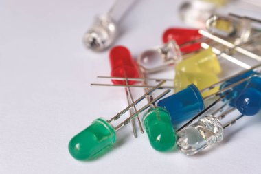 Renkli elektronik LED bileşenlerin makro görüntüsü kırmızı, yeşil, sarı, mavi, temiz beyaz bir yüzeye yayılmış. Elektronik, DIY teknolojisi ve devreleri çizmek için mükemmel.