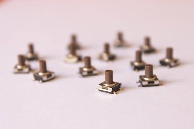Elektronik ve prototip kavramlarını resmetmek için ideal, beyaz bir yüzeyde düzenlenmiş çoklu kahverengi dokunsal anahtarların seçici odak resmi
