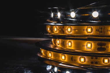 Parlayan bir LED şeridin detaylı makro görüntüsü. Bireysel diyotları ve basılı devre detaylarını gösteriyor. Modern ışıklandırma teknolojisi ve DIY elektroniği için ideal