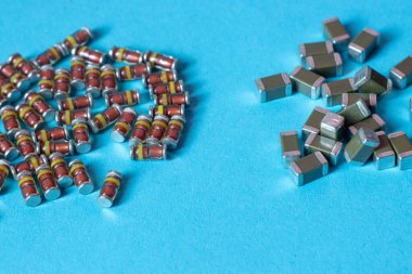 Canlı mavi bir yüzeye yerleştirilmiş çeşitli elektronik yüzey-monte diyotları ve kondansatörler. Elektronik, mühendislik veya donanım geliştirme konularının resimlendirilmesi için kullanışlıdır.