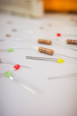  Elektronik bileşenlerin dikey yakın çekimi. Beyaz bir yüzeye yayılmış rezistanslar ve LED 'ler de dahil. Elektronik, DIY projeleri, BTMM eğitimi ve teknolojide kavramları resmetmek için ideal.